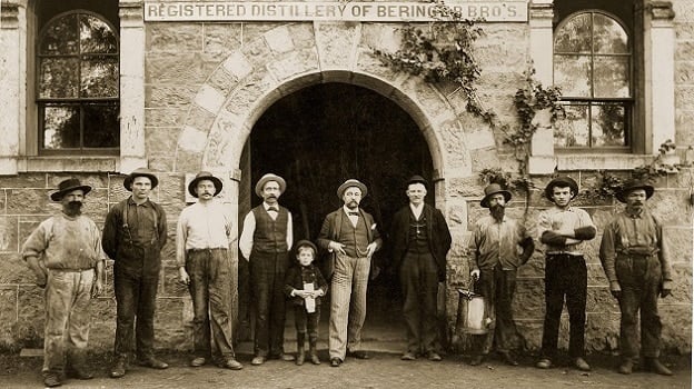 Historic distillery workers standing outside stone building