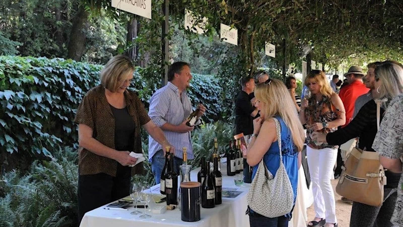 People tasting wine at outdoor event.