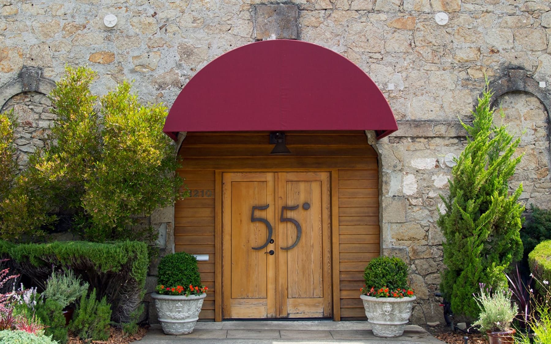 Stone building with red awning and wooden doors.