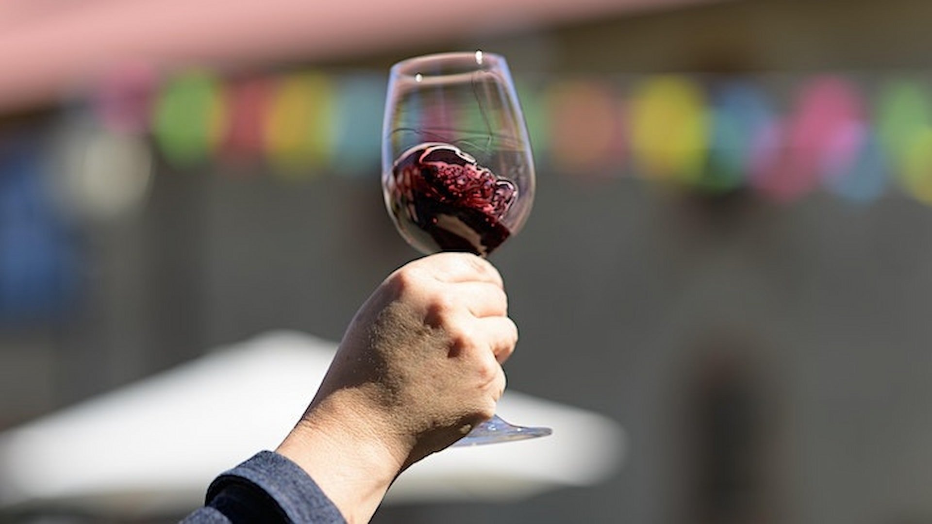 Hand holding glass of red wine outdoors