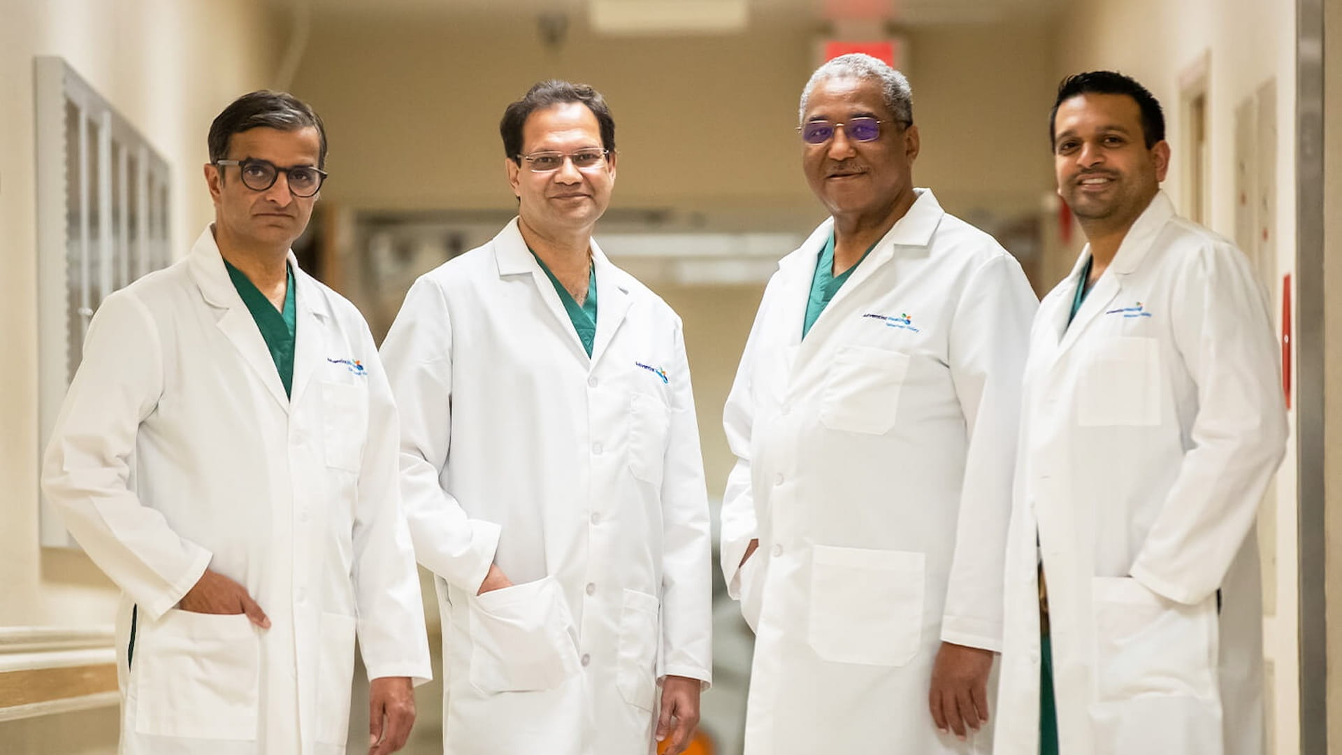 Four doctors in white coats standing in hallway