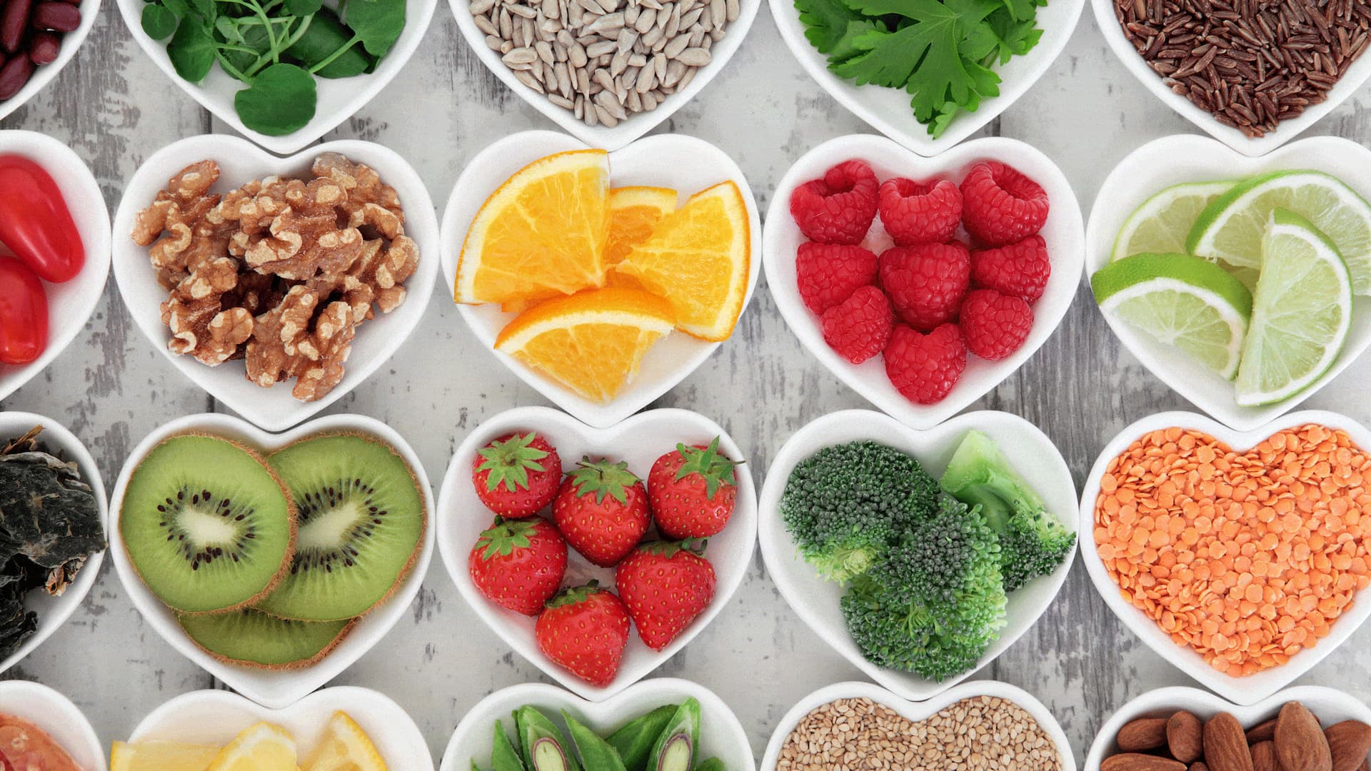 Heart-shaped bowls with fruits and nuts variety.