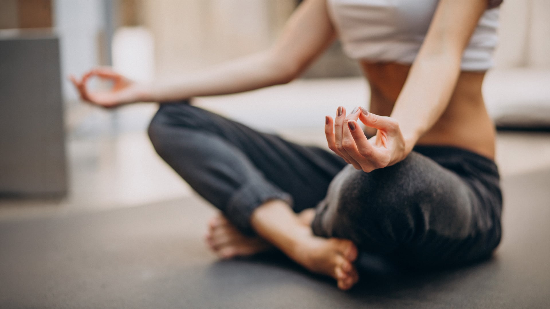 Woman meditating cross-legged on floor with relaxed hands