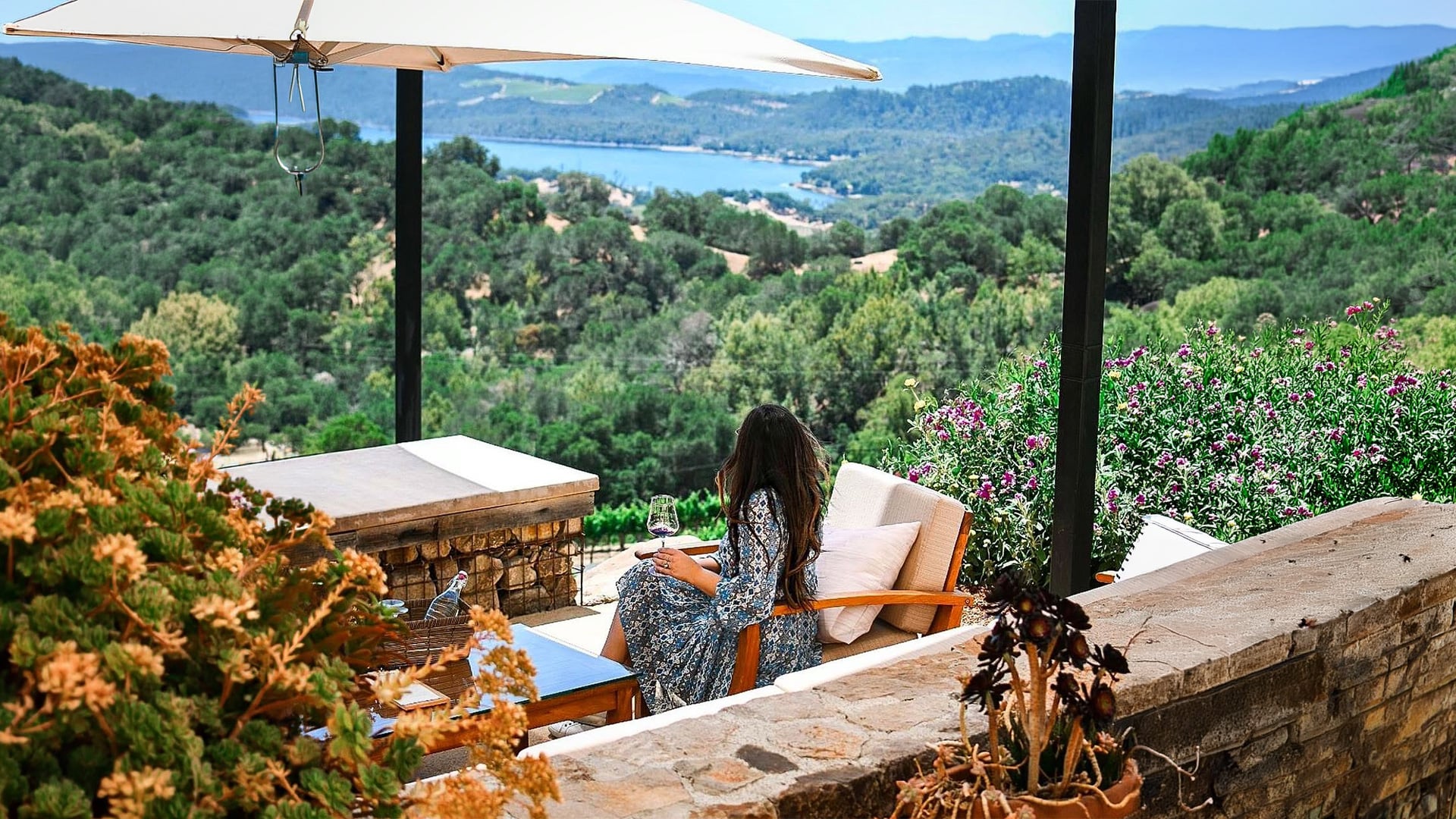 Woman enjoying wine overlooking lush lake valley