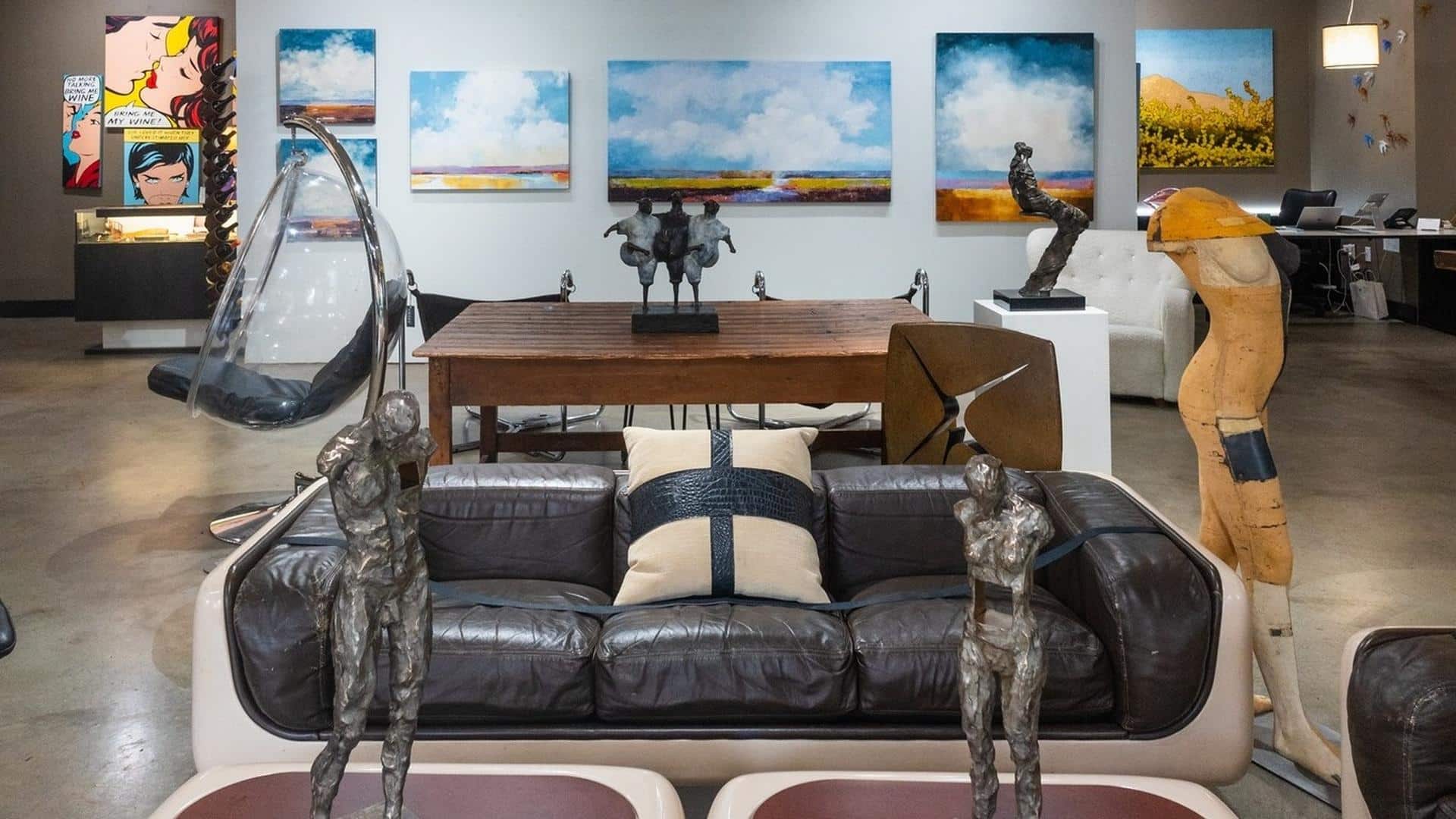 Art gallery with sculptures and paintings on display.