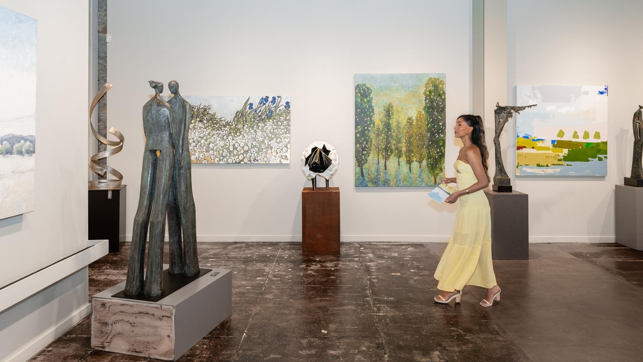 Woman admiring sculptures and paintings in art gallery.
