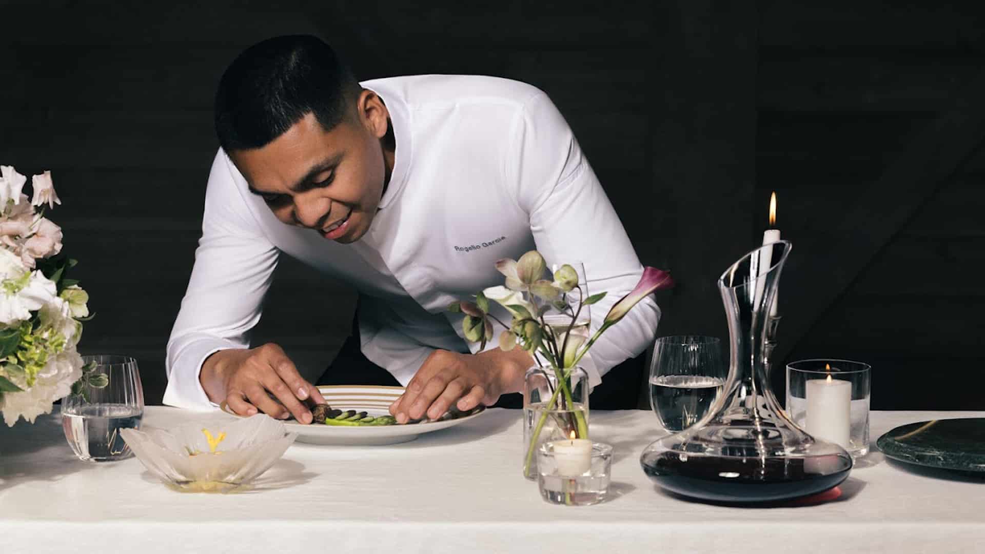 Chef carefully preparing gourmet dish at table.