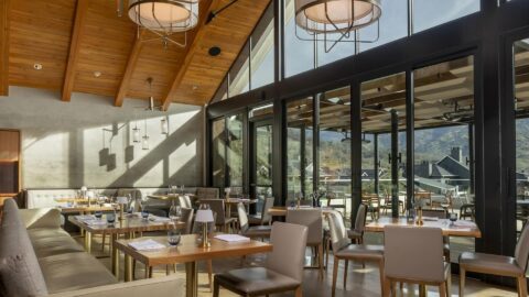 Modern restaurant with wooden ceiling and large windows.