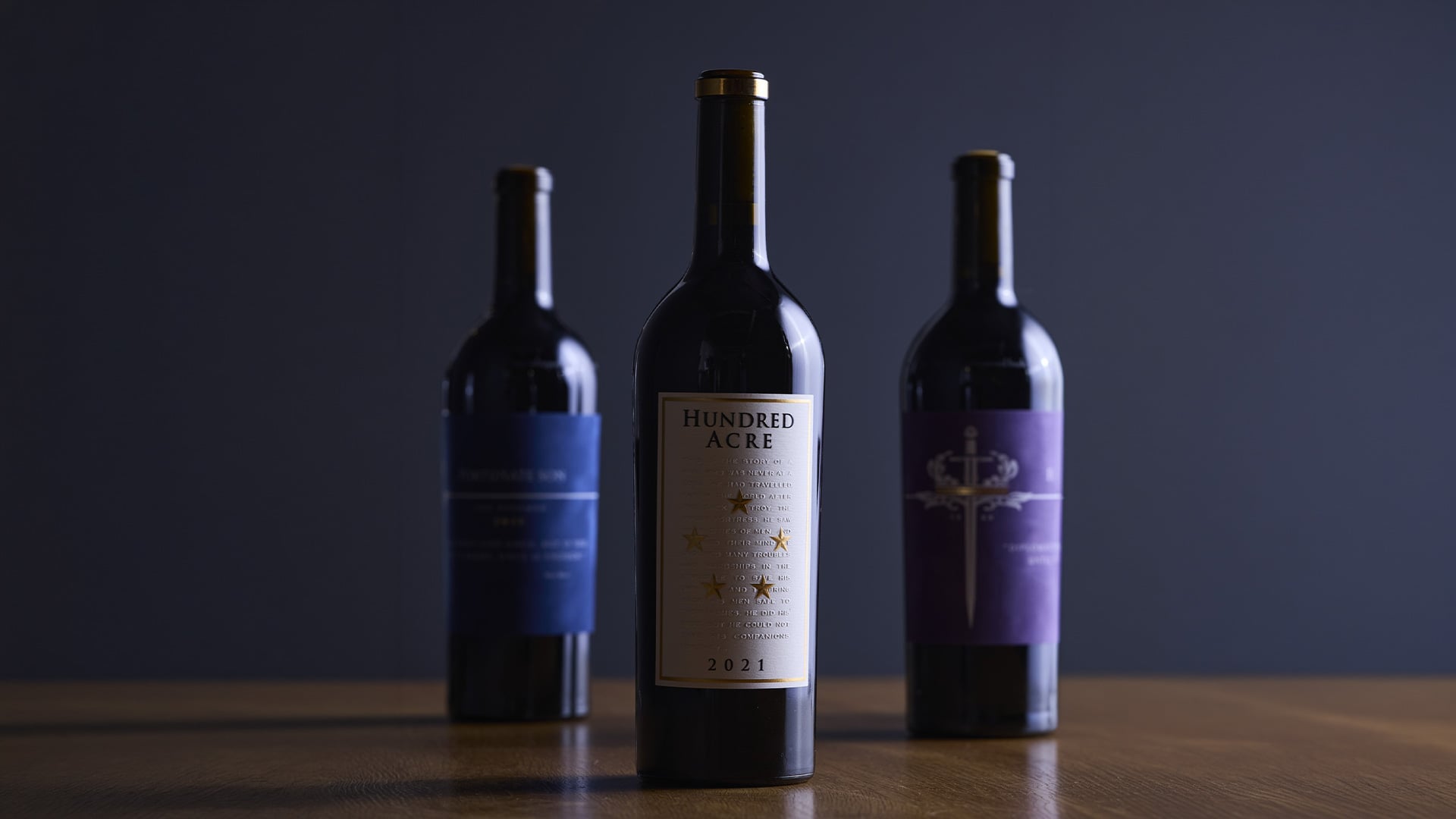 Three wine bottles with Hundred Acre 2021 centered