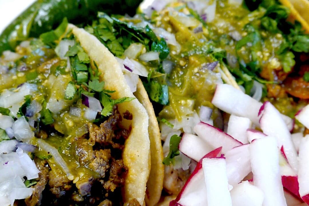 Tacos with green salsa, onions, and radishes