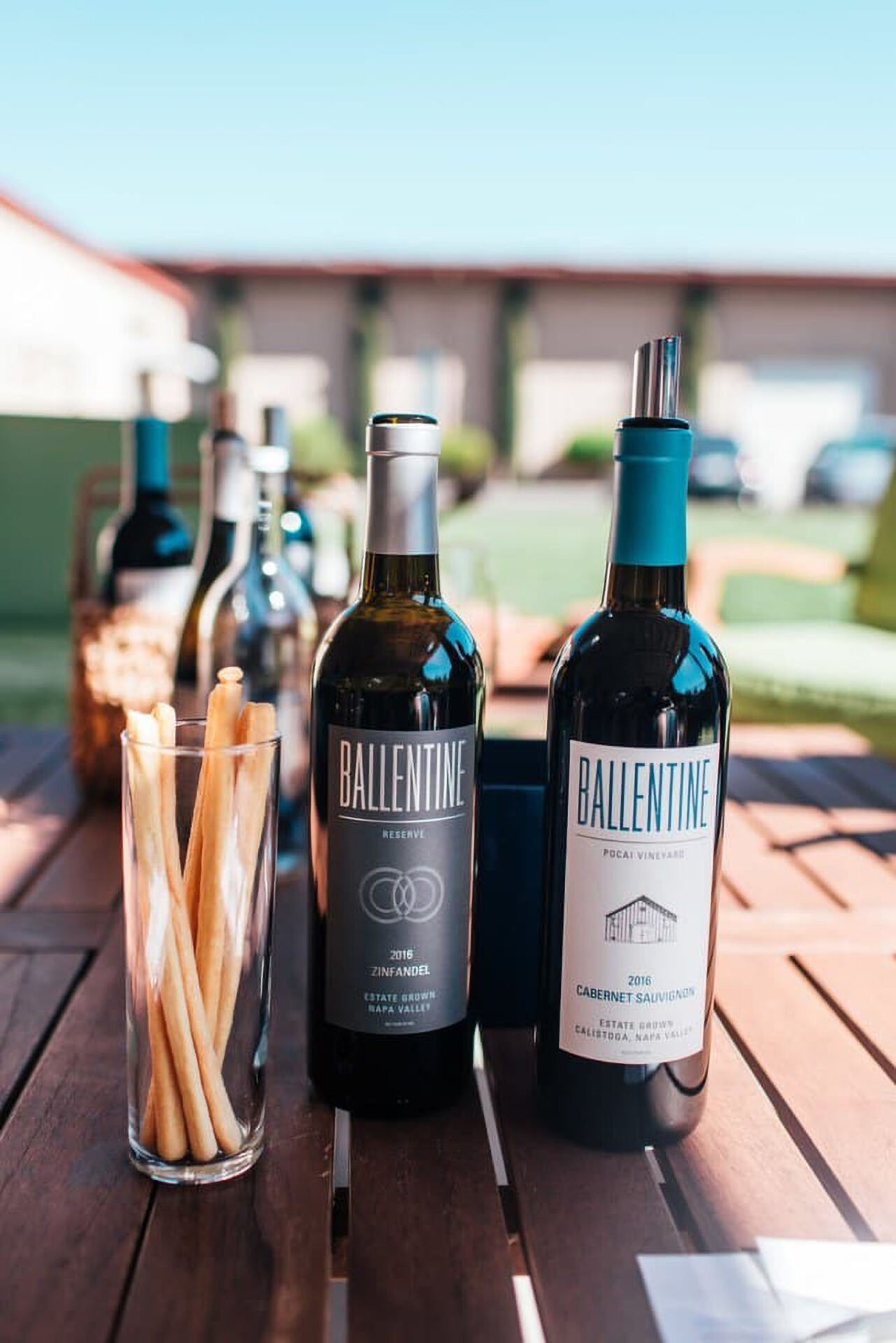 Ballentine wine bottles and breadsticks on outdoor table.