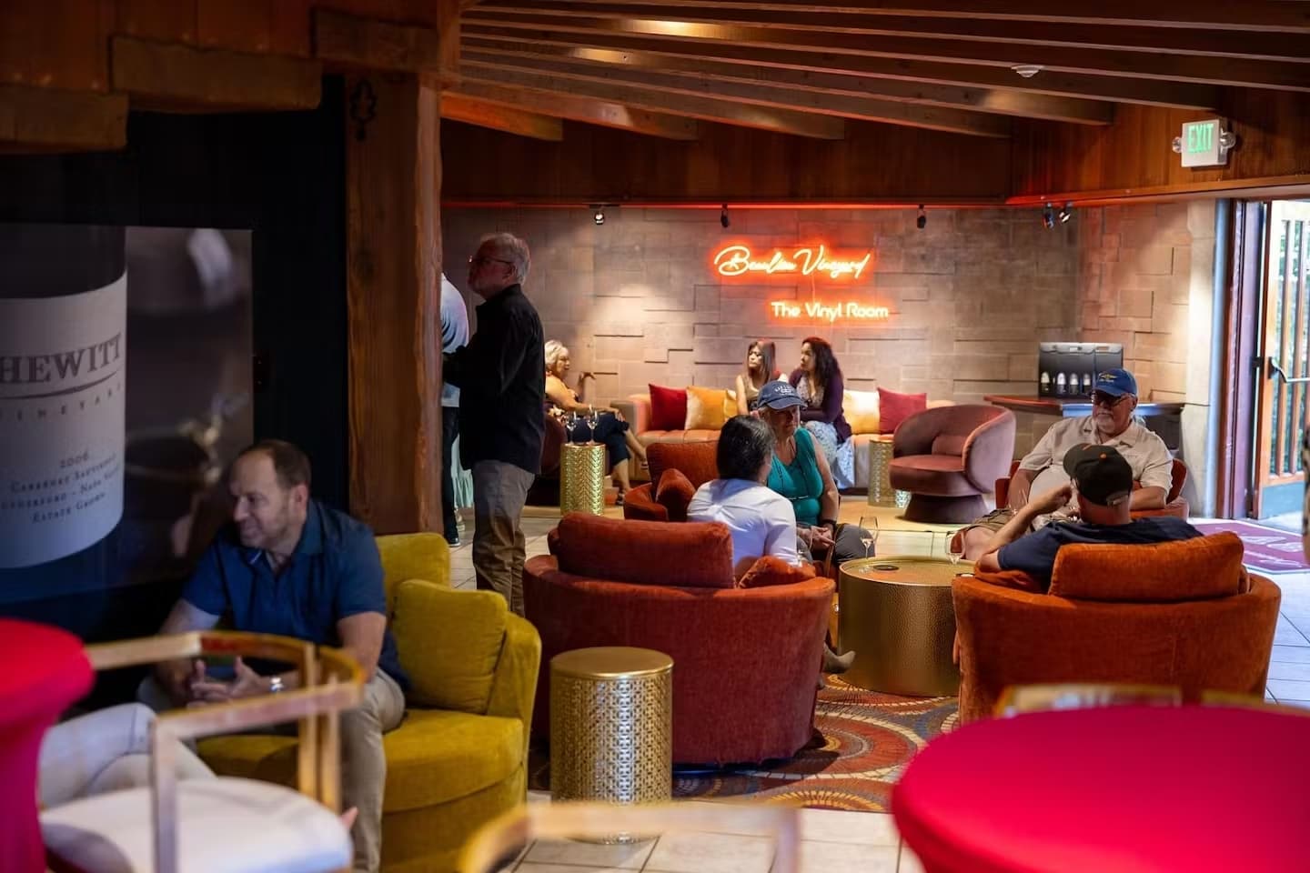 People relaxing in cozy lounge with neon sign.