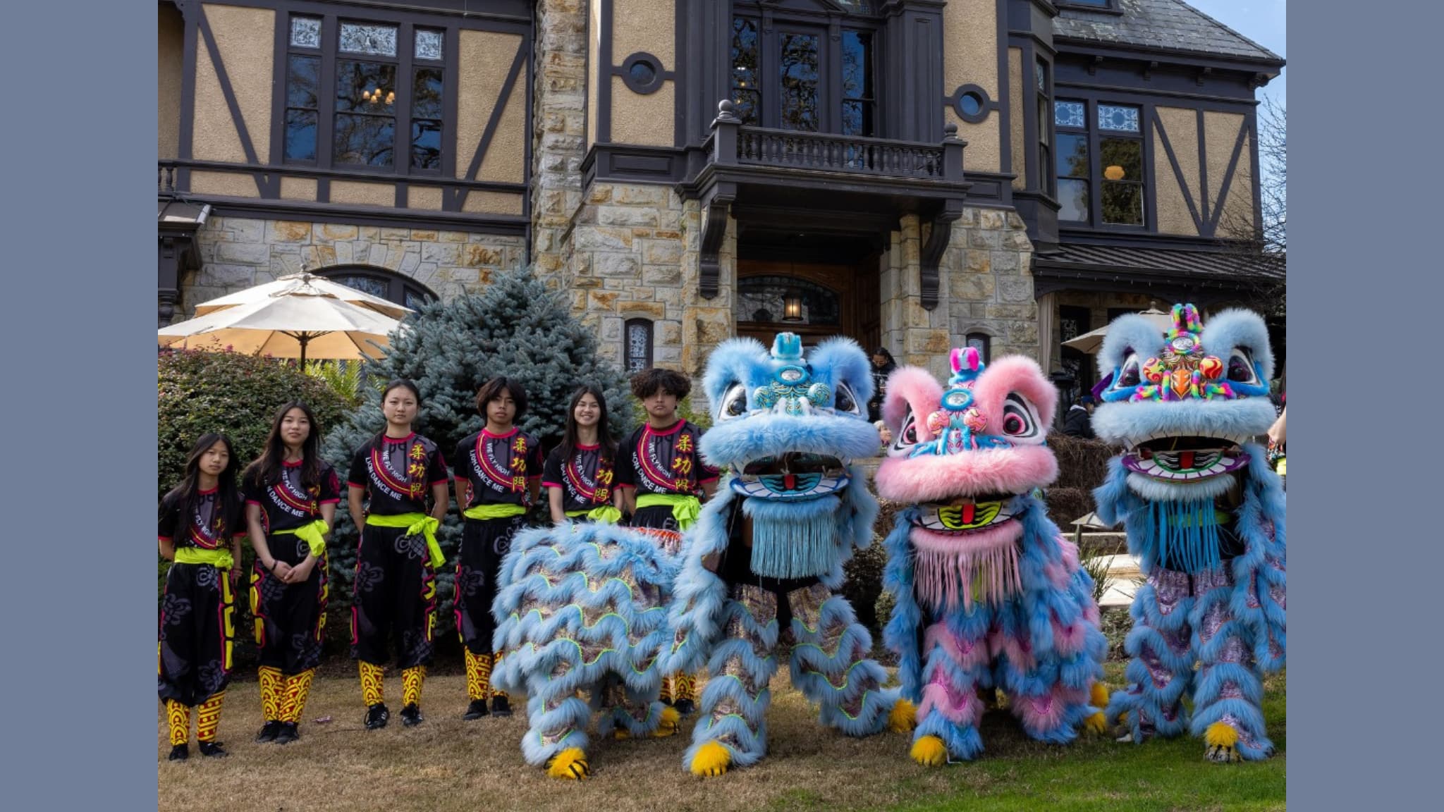 Lion dance performers posing outside a large house