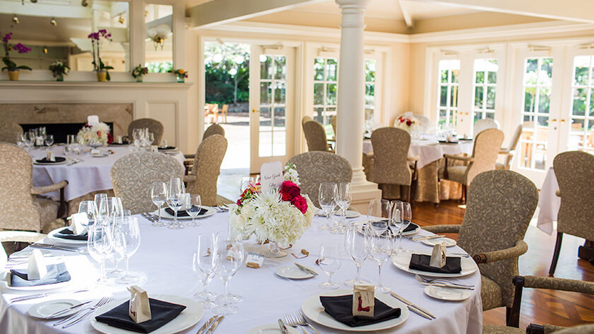 Elegant dining room with set tables and flowers.