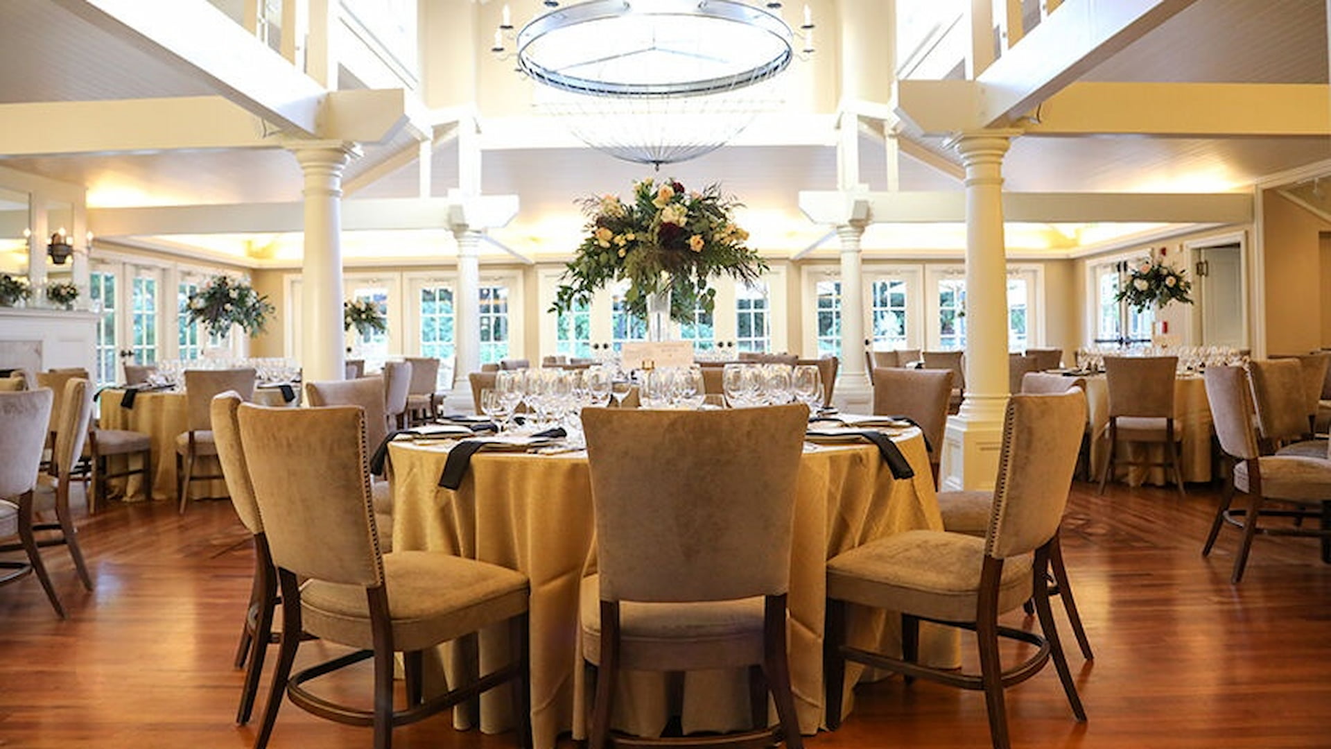 Elegant banquet hall with round tables and flowers.