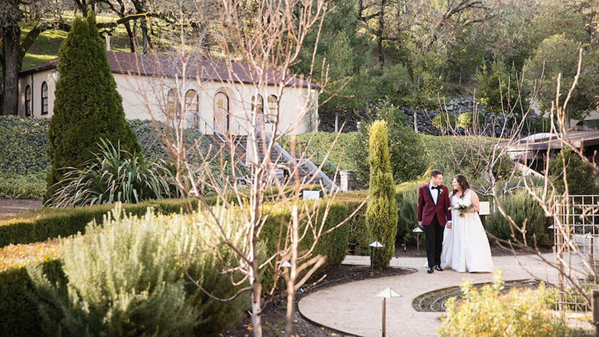 Bride and groom walking in a garden.