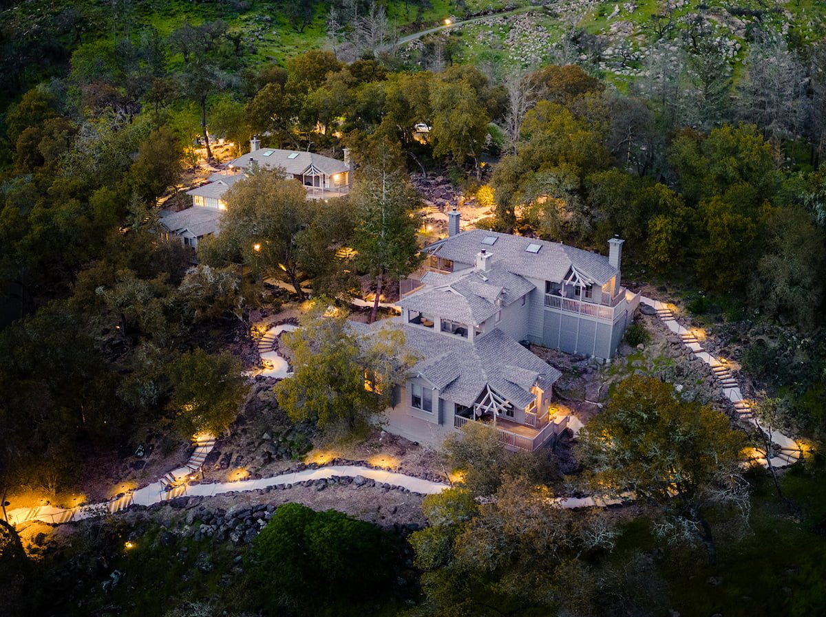 Aerial view of illuminated forest retreat at night.