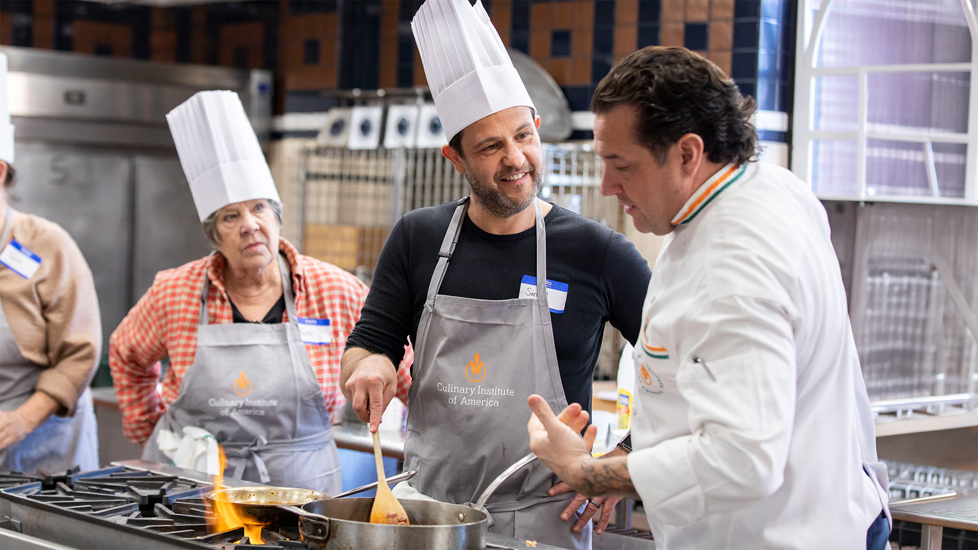 Chefs instruct students cooking over stovetop flames