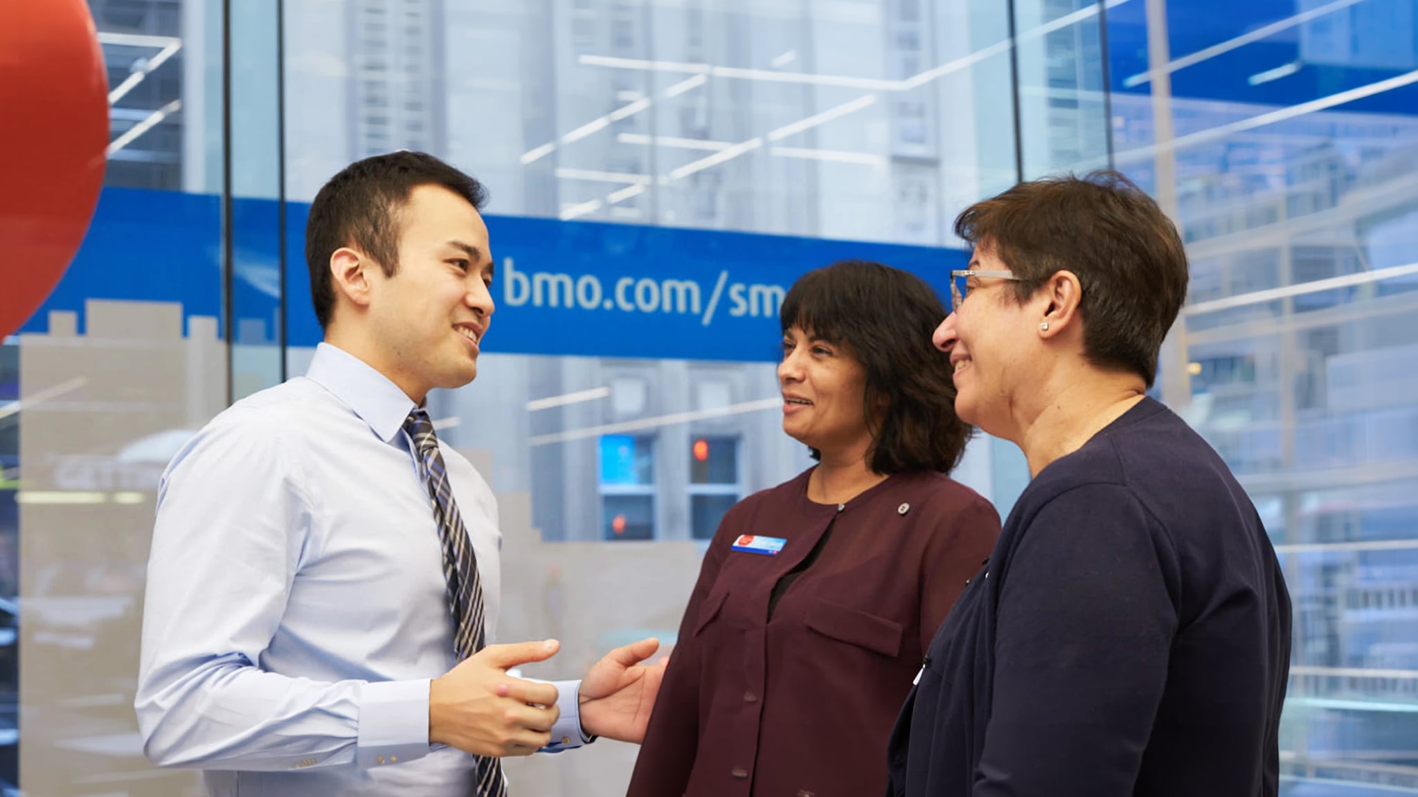 Bank representative speaking with two customers indoors