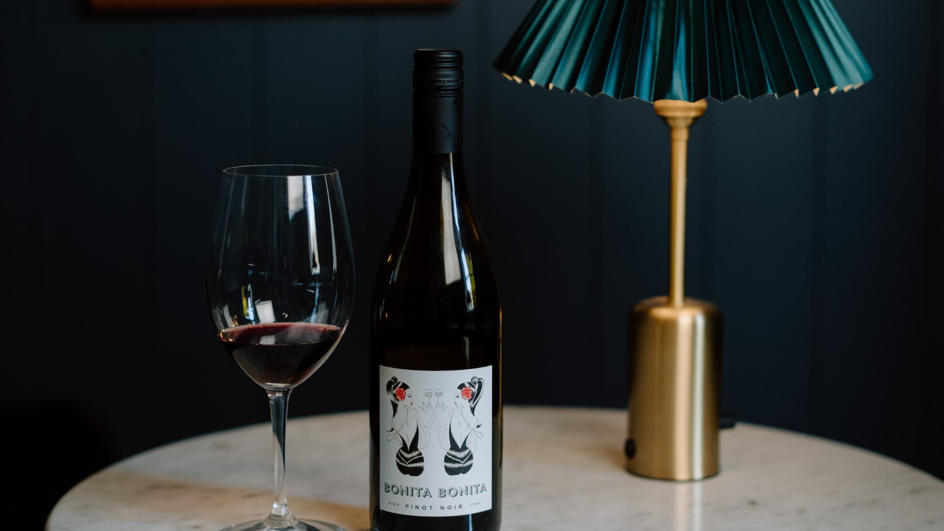Bottle of wine with glass on table.