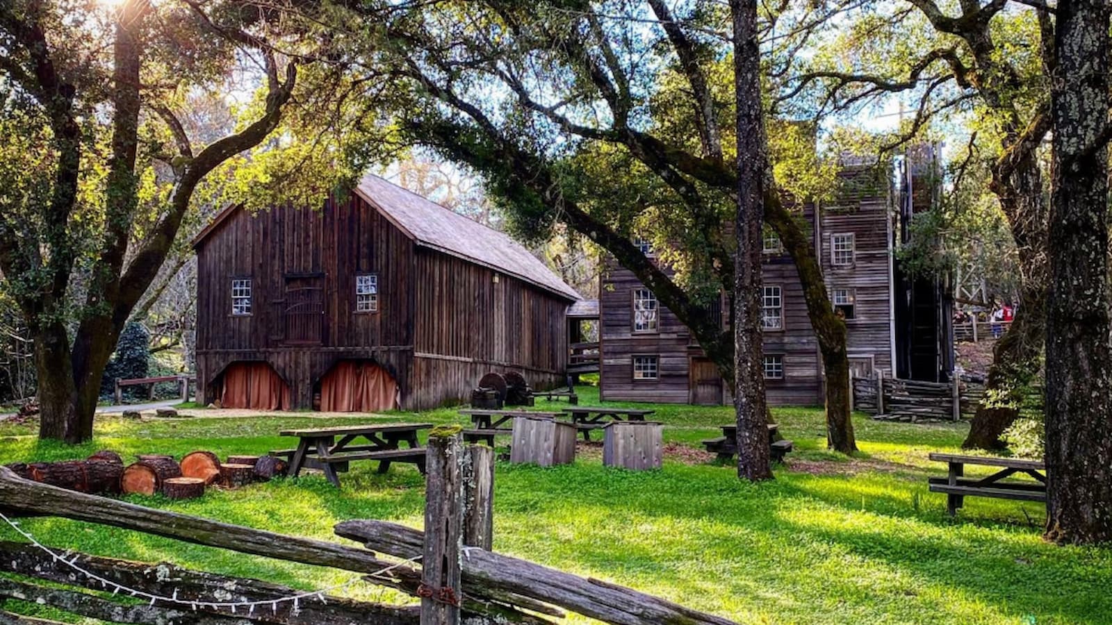 Historic wooden buildings in a lush green park.