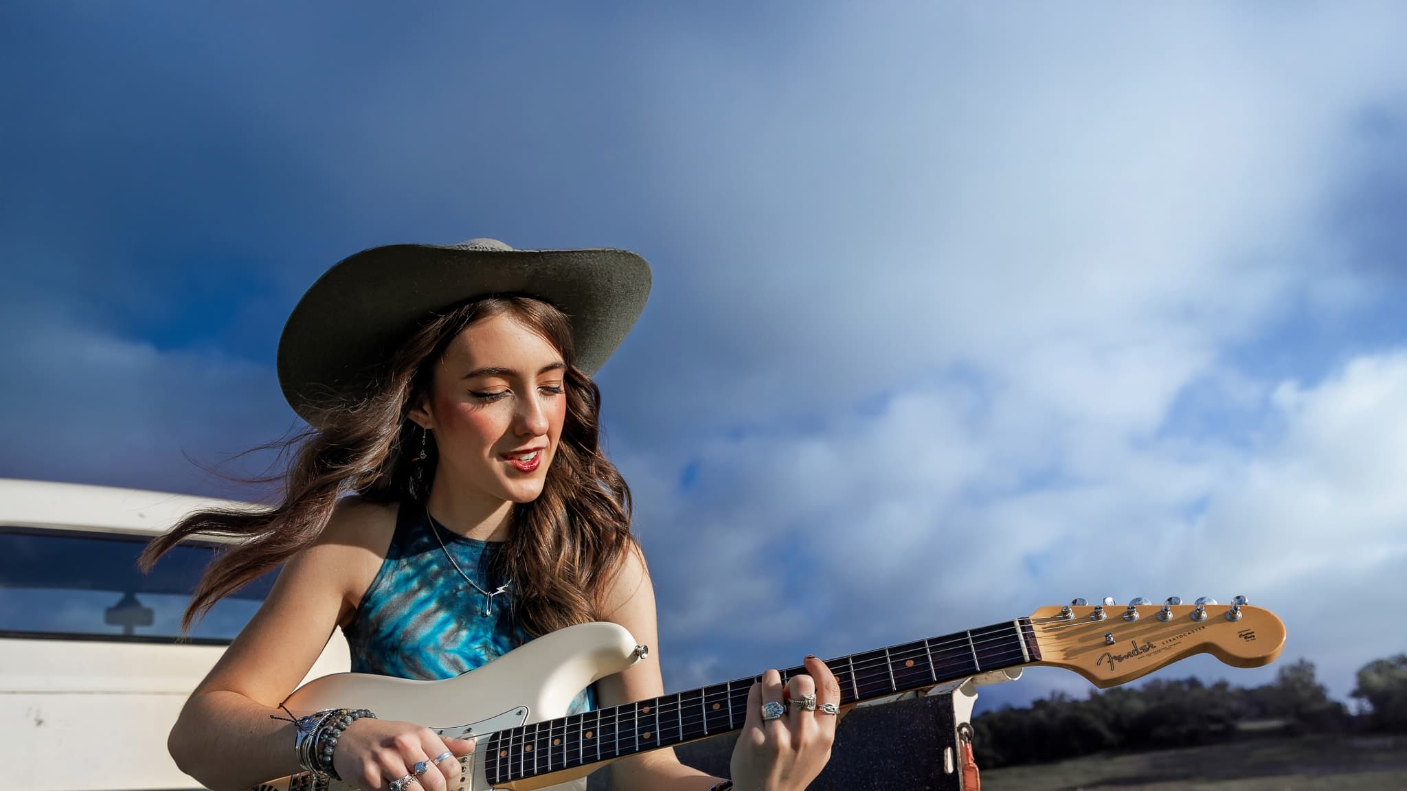 Woman playing electric guitar outdoors.