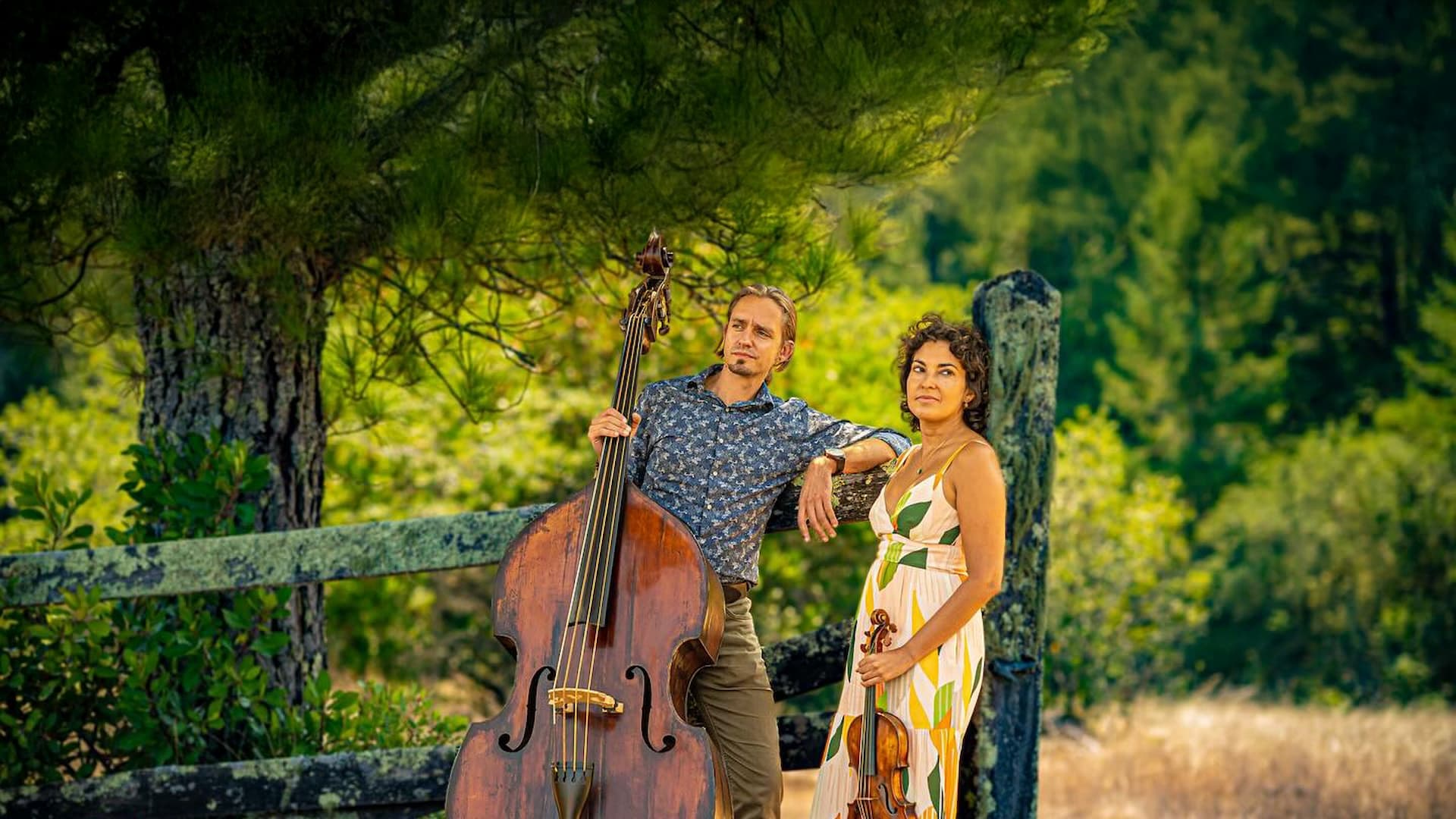 Two musicians in nature with cello and violin.
