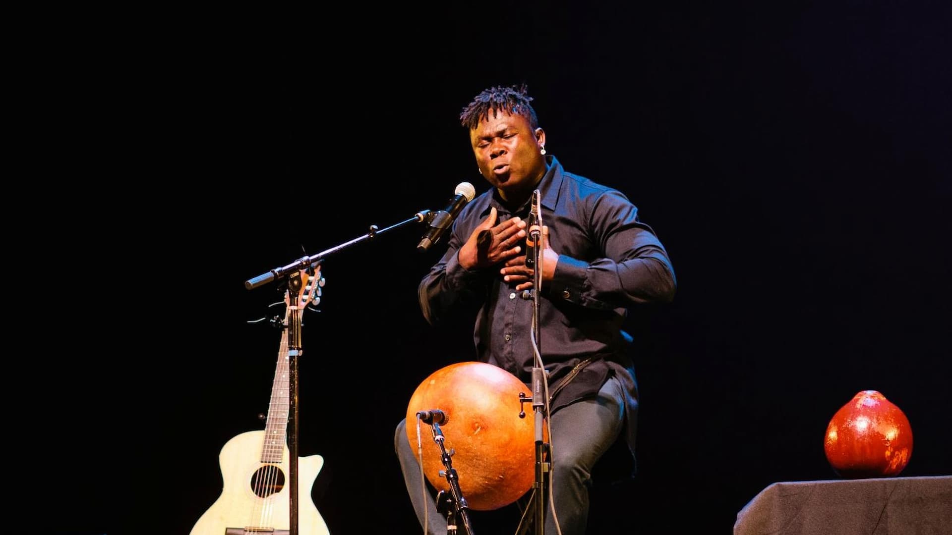 Man passionately performing music on stage with instruments.