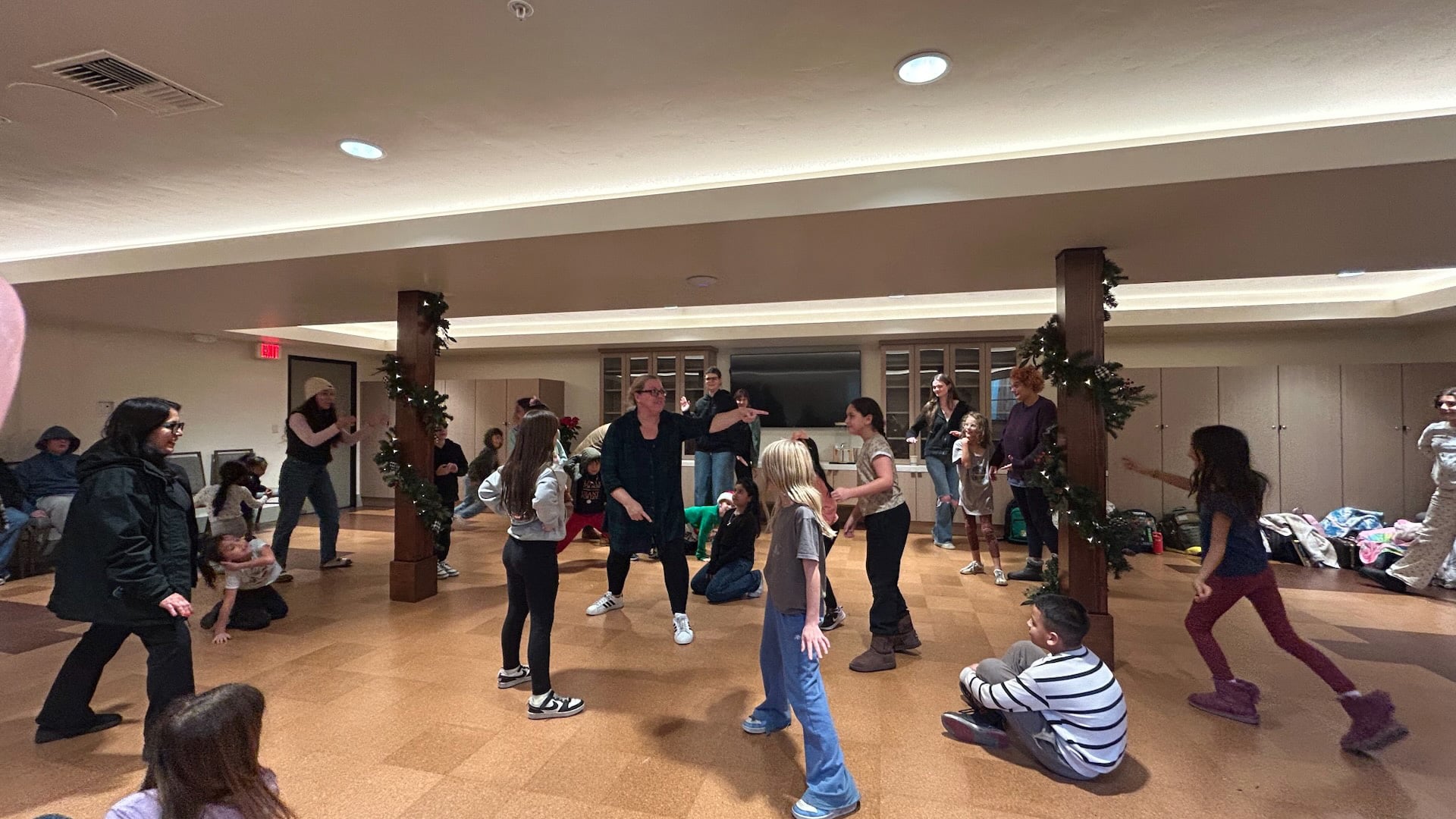 Children and adults dancing at an indoor holiday gathering