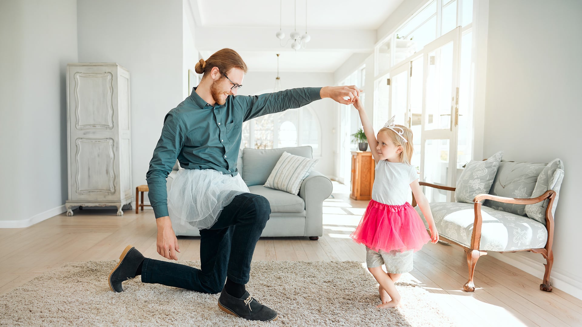Father and daughter dance together wearing playful tutus