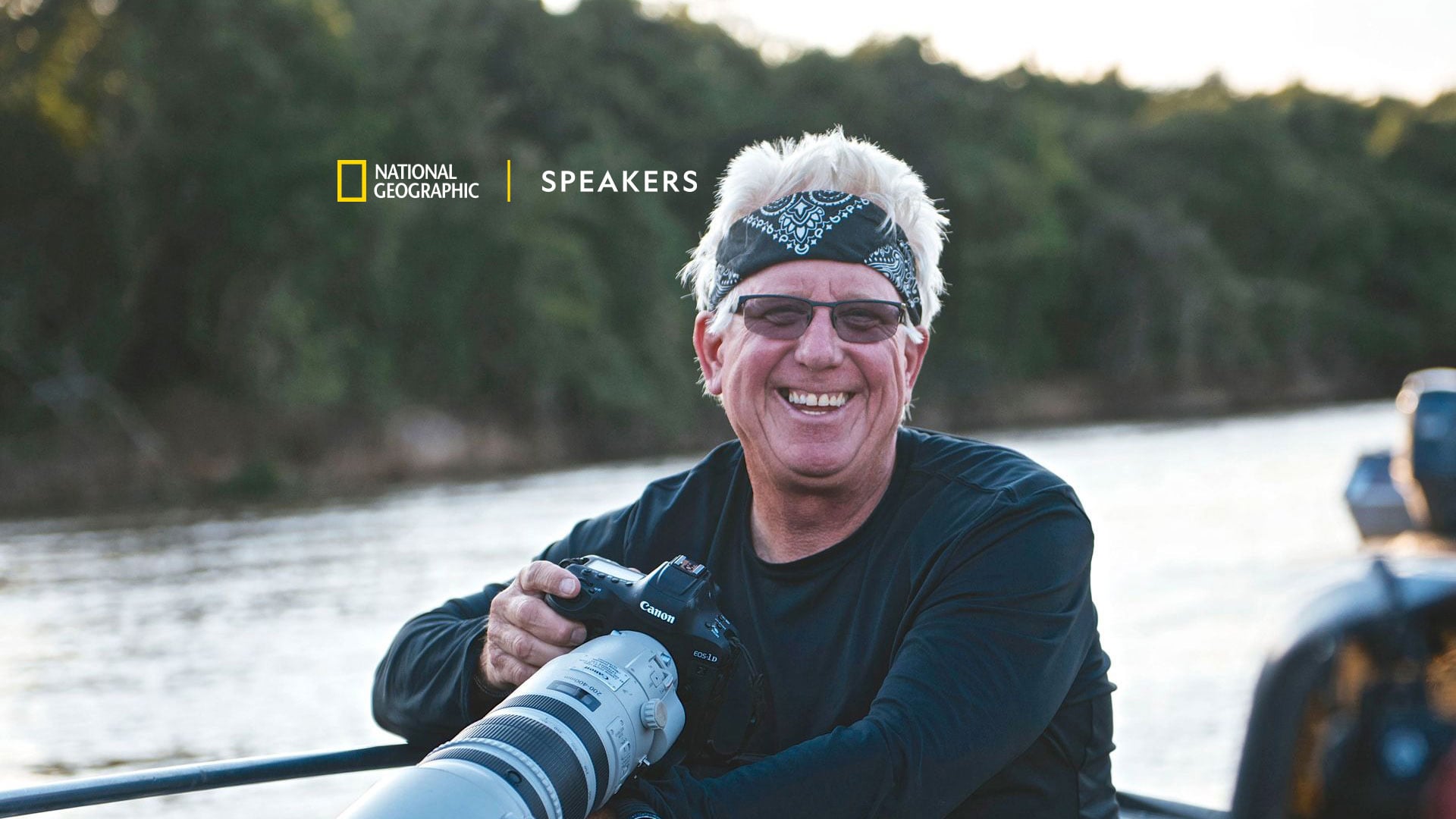 Smiling photographer holds camera on boat by river