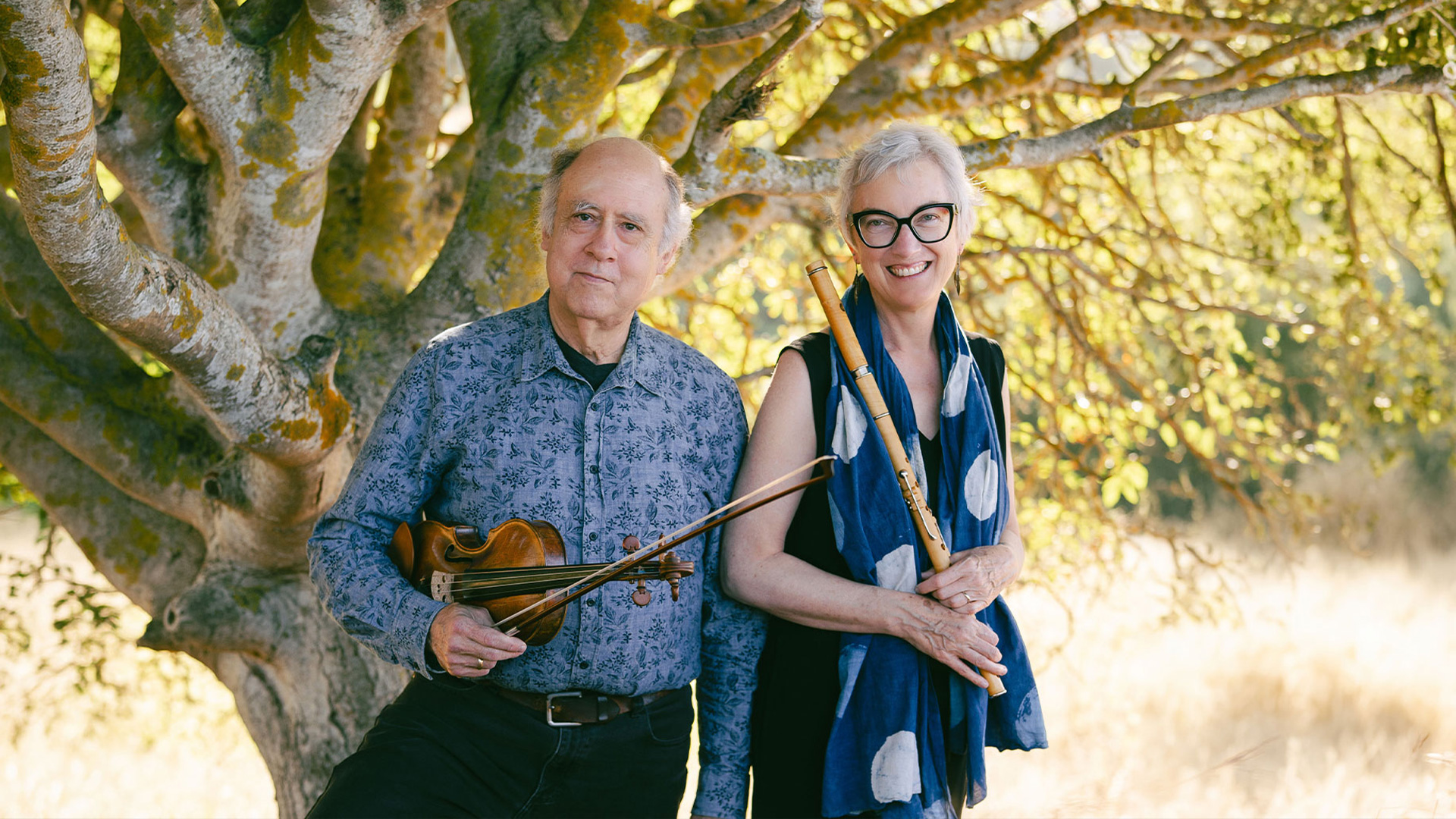 Two musicians holding violin and flute outdoors