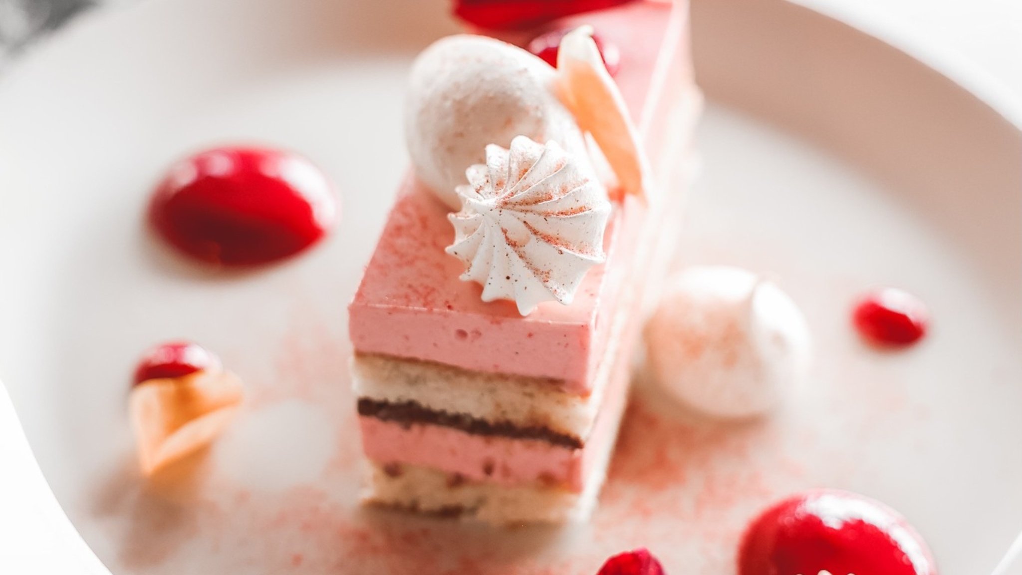 Layered strawberry mousse cake with meringue garnish.