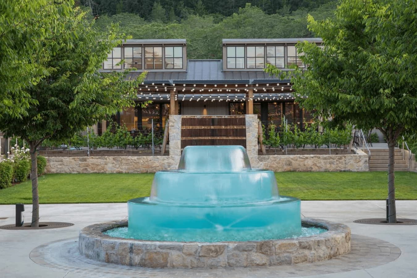 Tiered turquoise fountain before modern rustic building