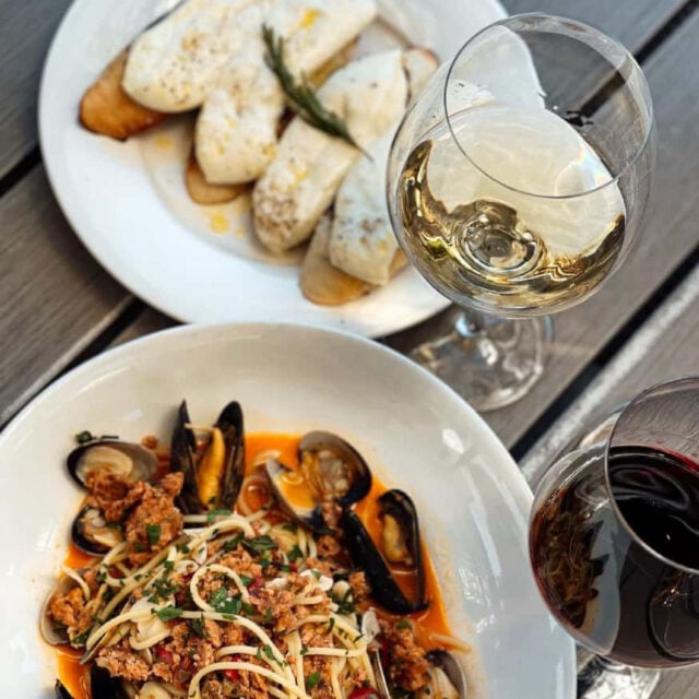 Pasta dish with mussels and two glasses of wine.