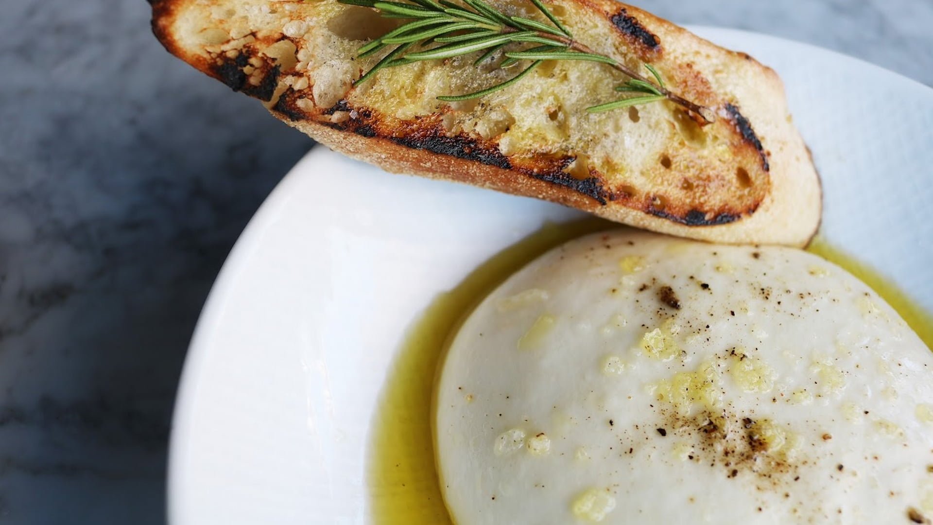 Grilled bread with burrata cheese and olive oil.