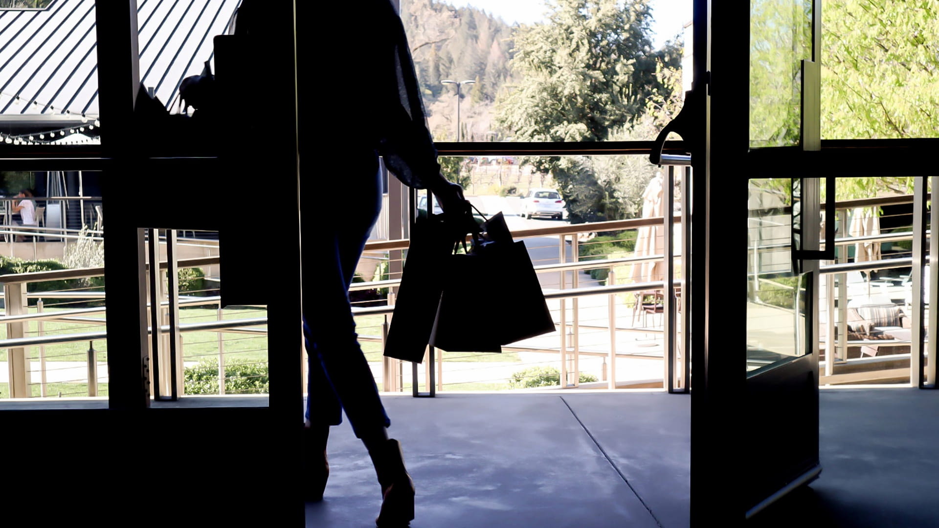Person exiting store carrying shopping bags.