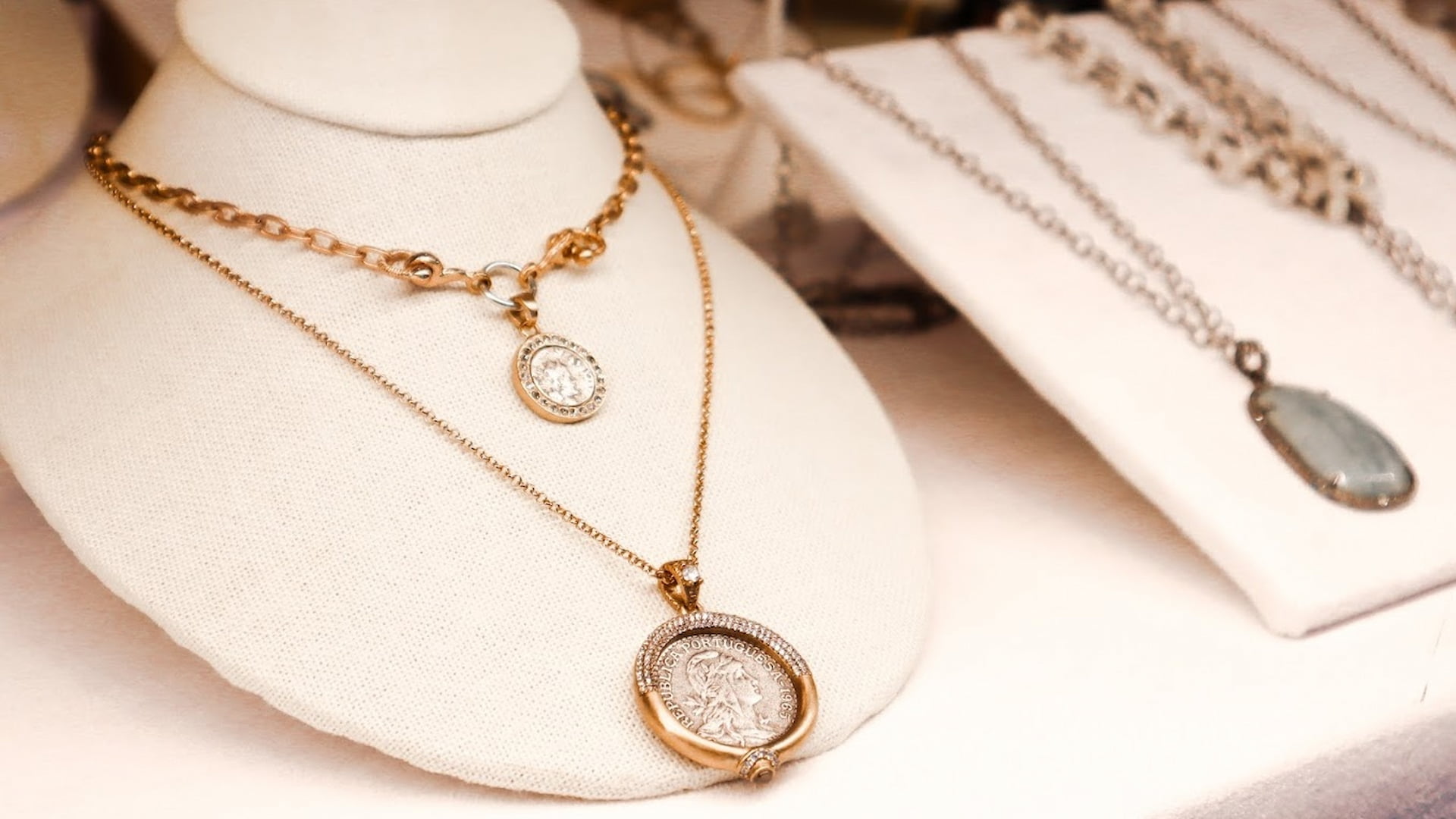Elegant gold coin necklaces on display stands.
