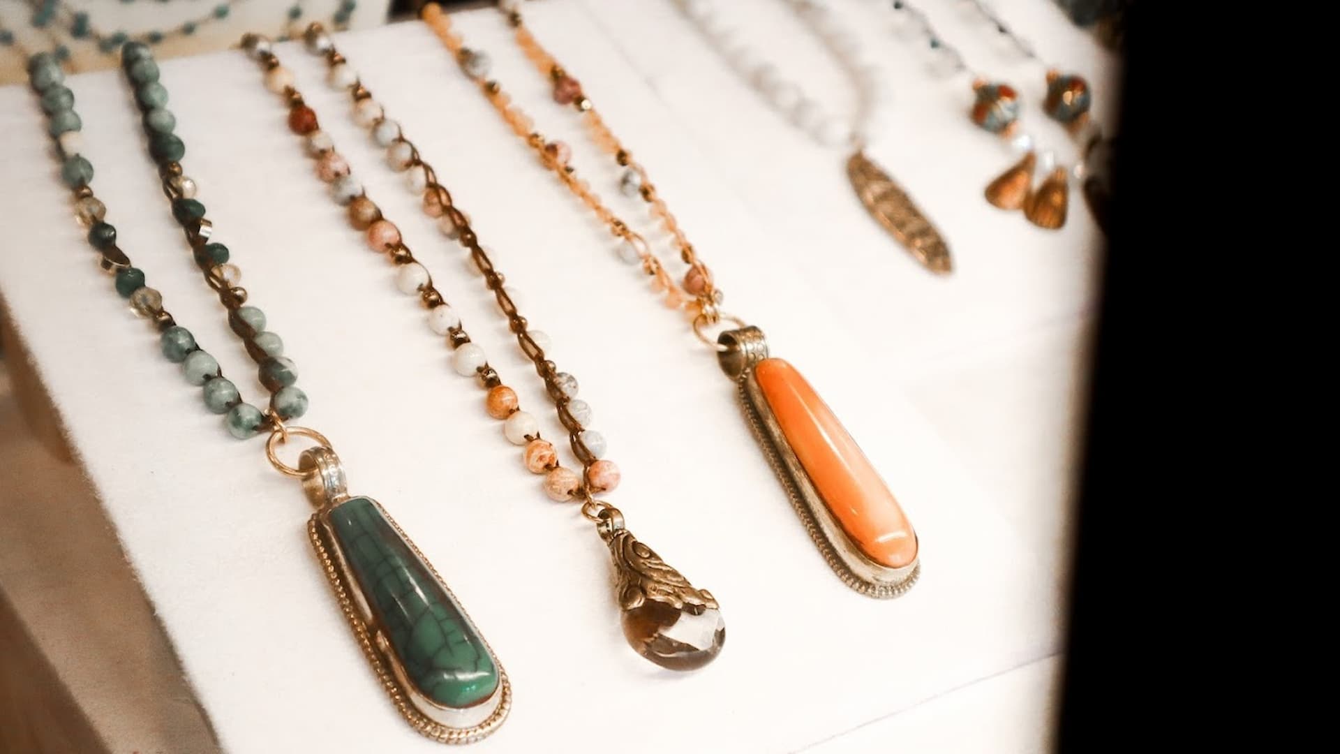 Colorful gem necklaces displayed on white surface.