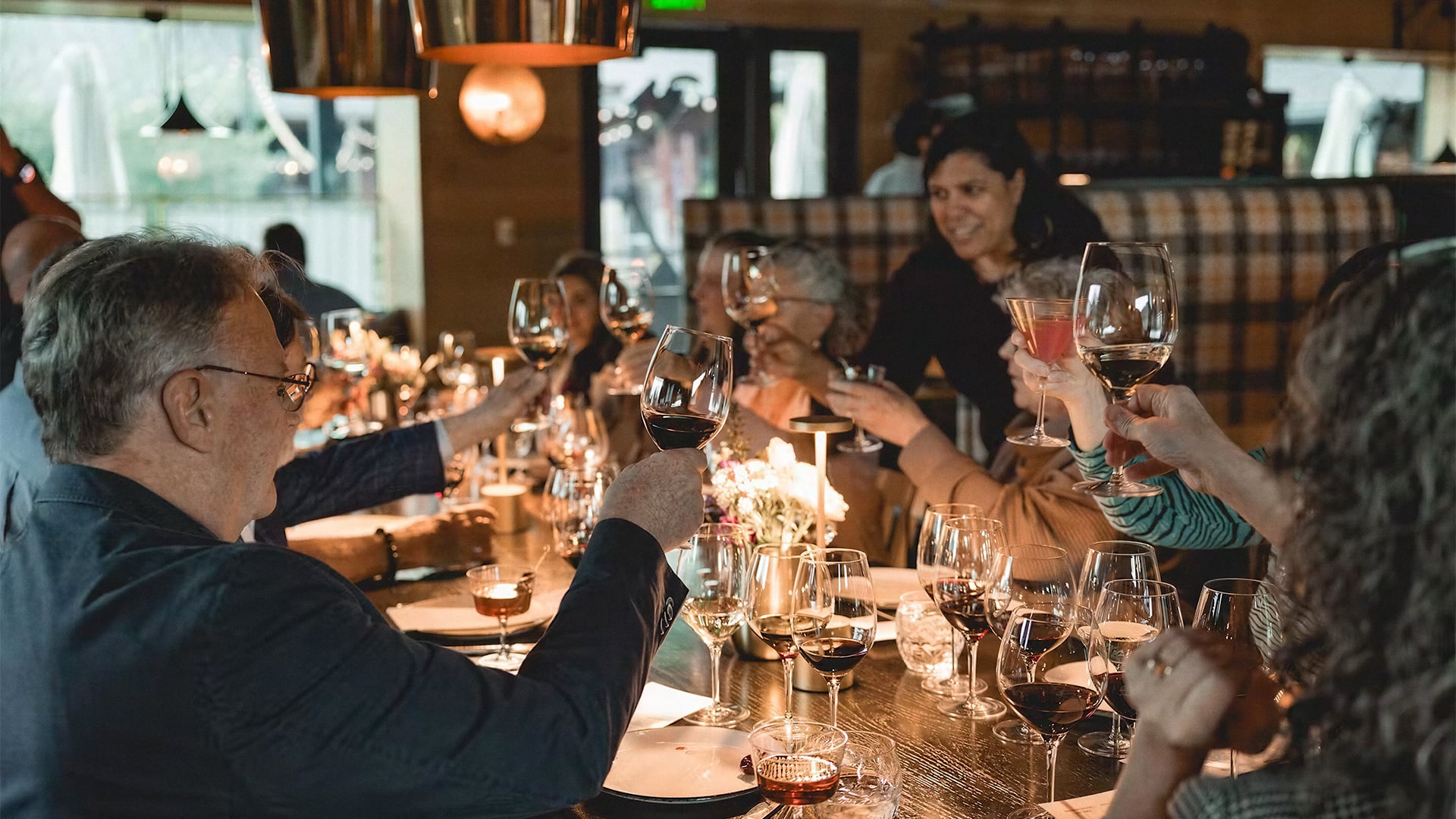 Friends toast with wine at a warmly lit restaurant