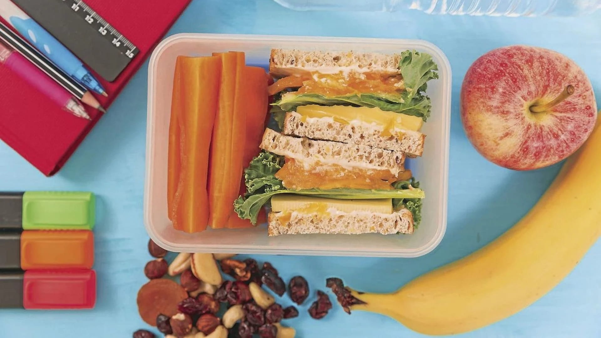 Healthy lunchbox with sandwich, fruits, and vegetables.