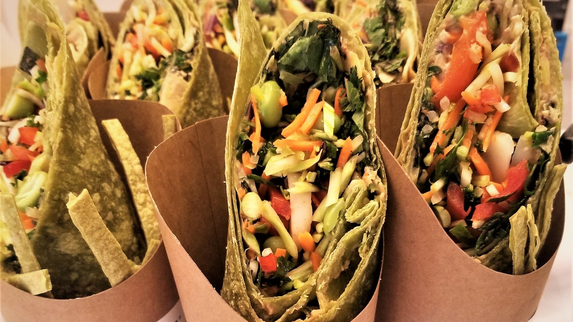 Fresh vegetable wraps in brown paper holders.