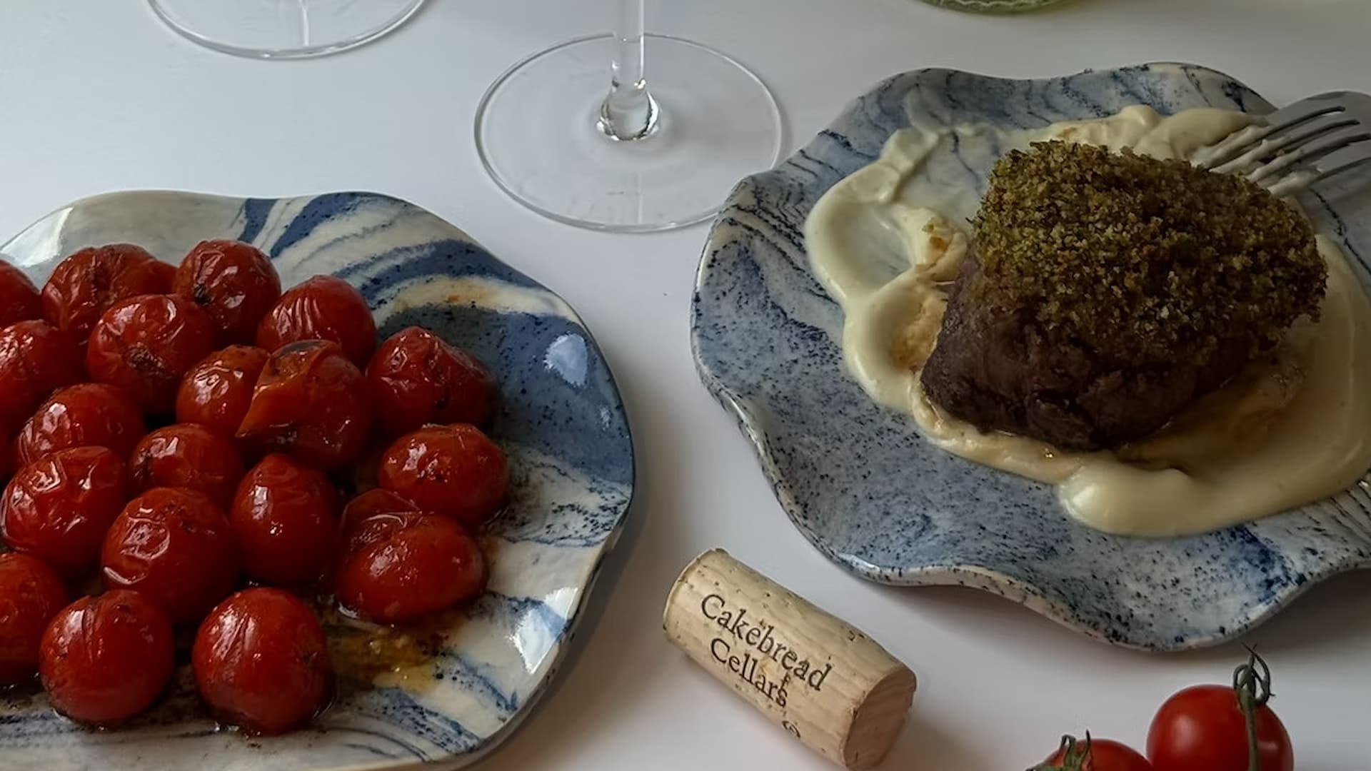 Steak with sauce, roasted tomatoes, wine cork on table.