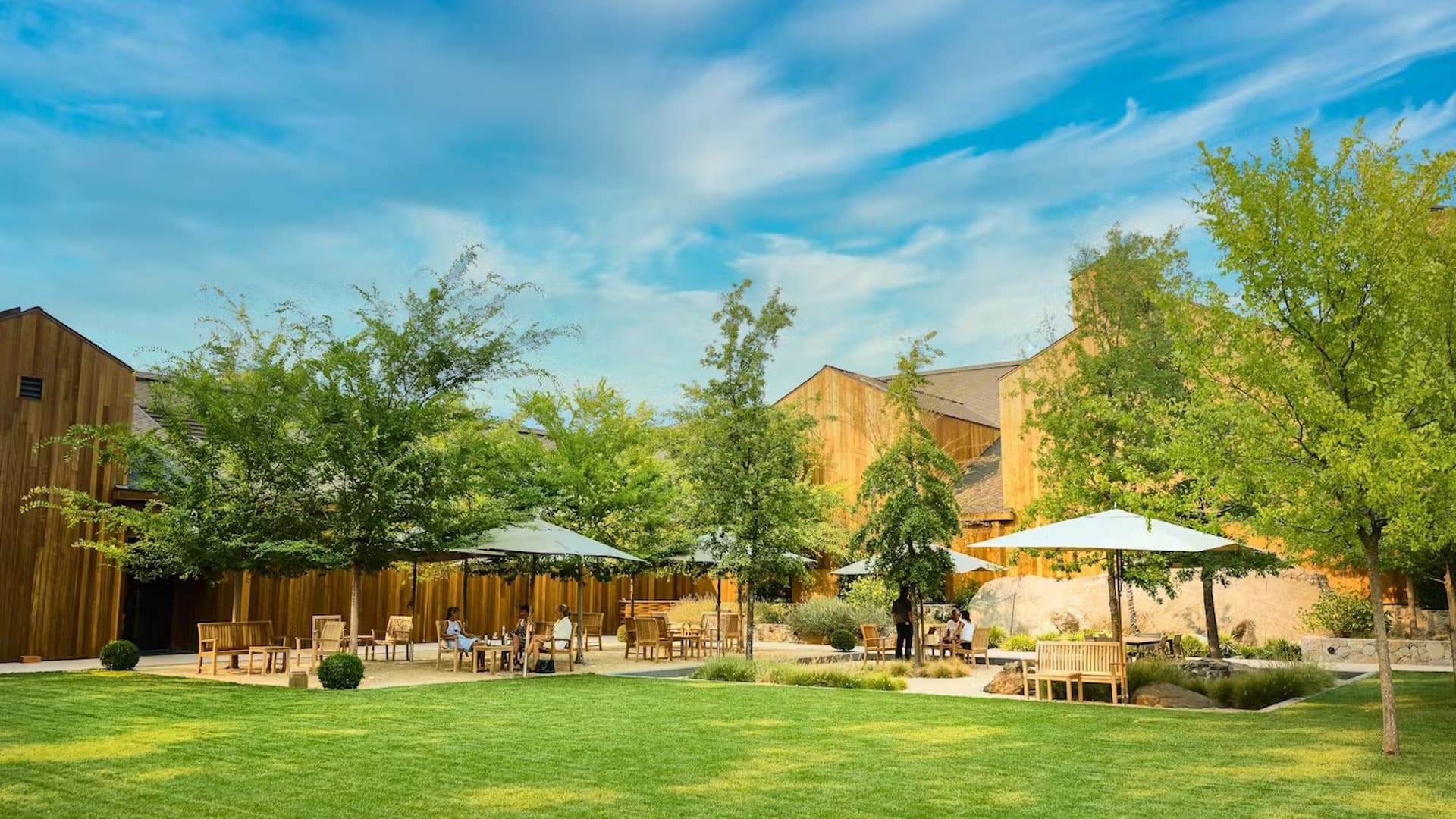 Outdoor seating area with trees and wooden buildings.