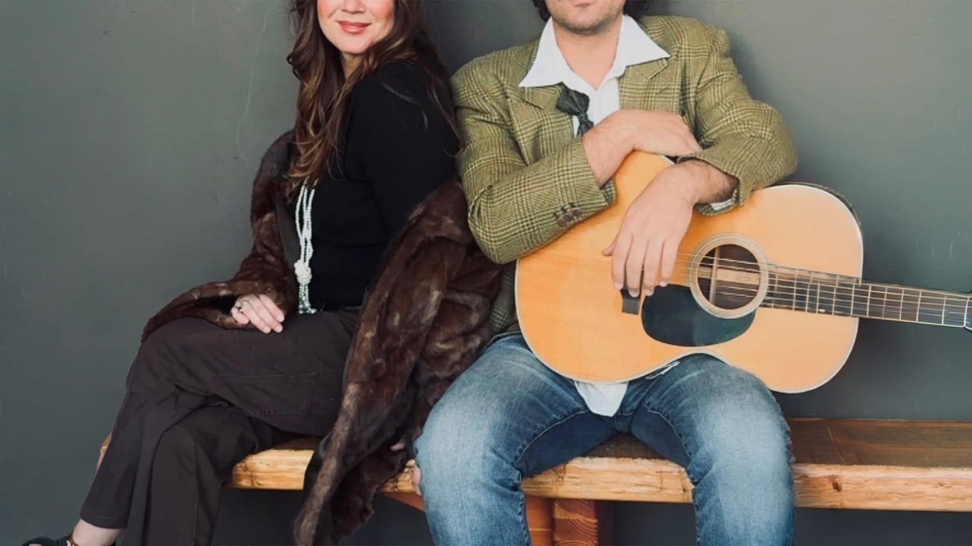 Couple sitting on bench with acoustic guitar