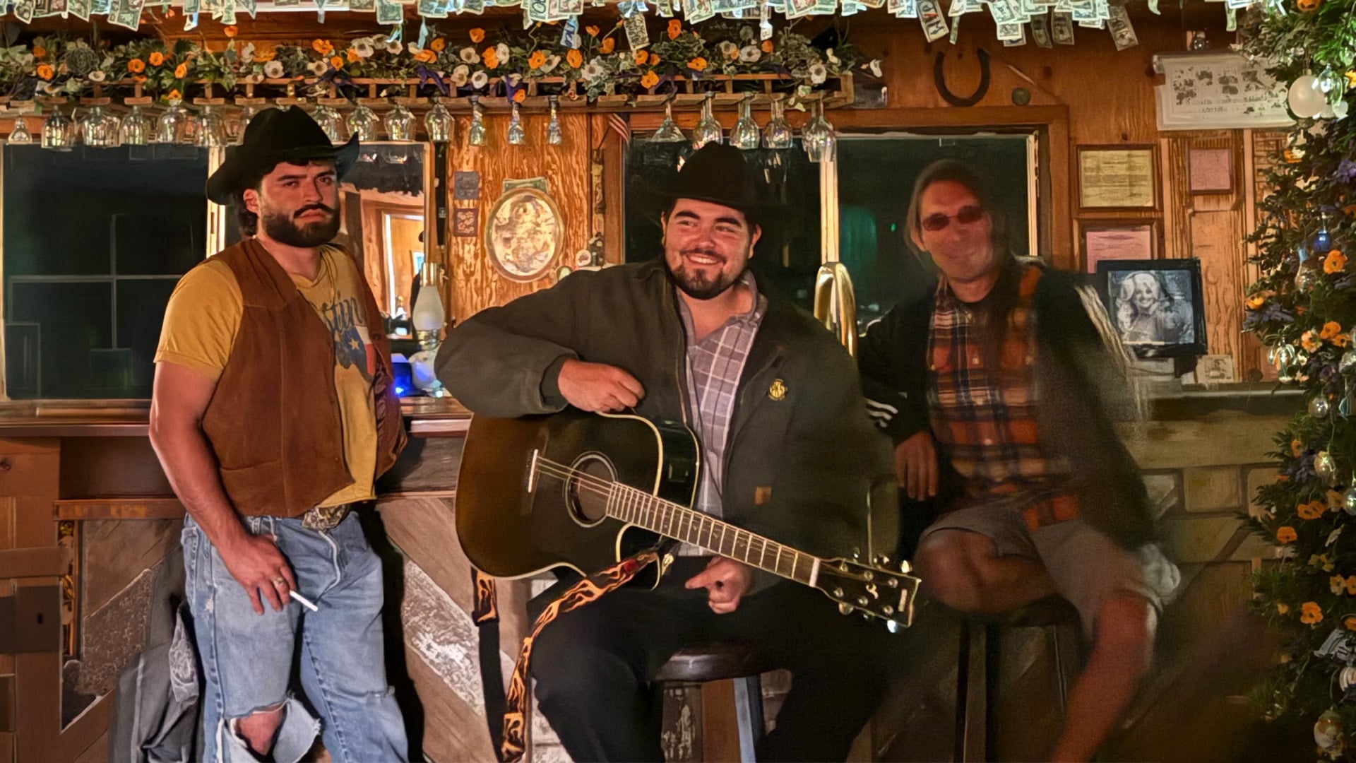 Three men in rustic bar with guitar