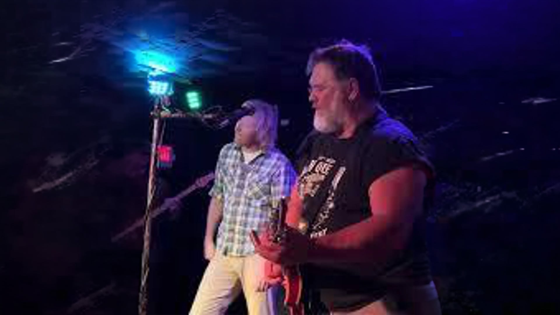 Two musicians performing on stage under blue lights