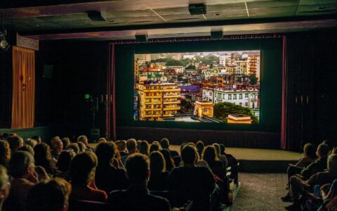 Audience watching cityscape movie in theater.
