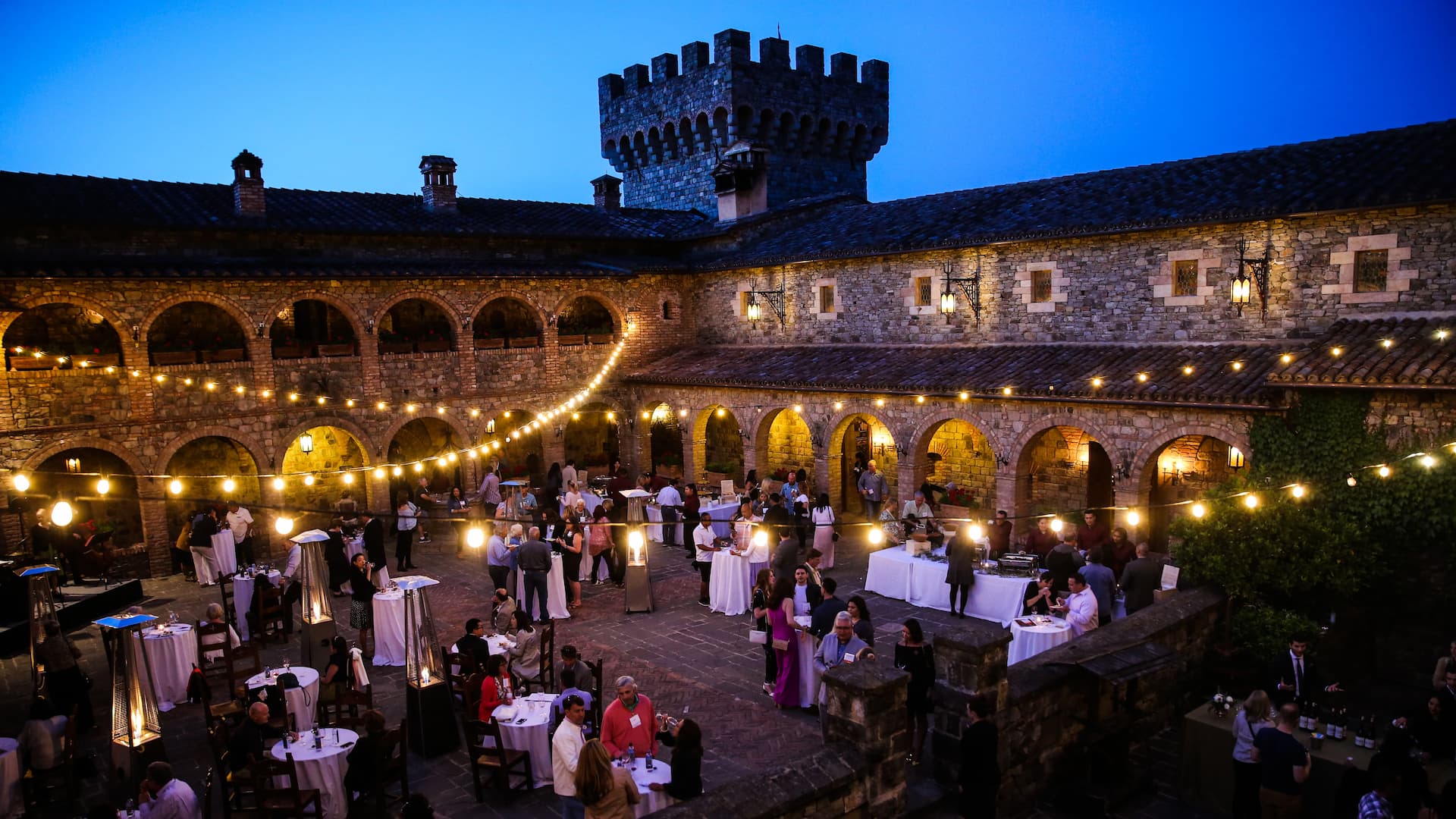 Evening courtyard event with string lights and guests.