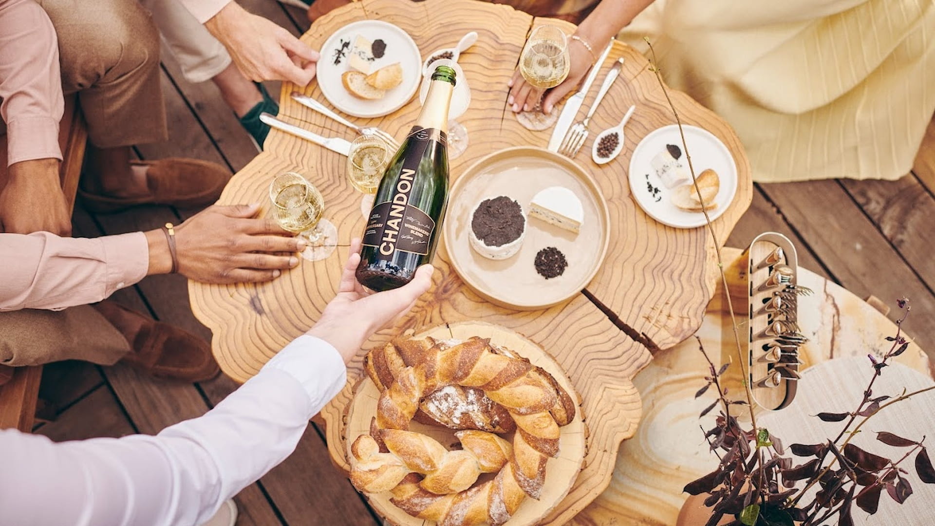 People enjoying wine and cheese at a wooden table.